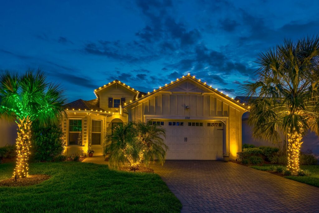 Holiday landscape lighting on trees and shrubs outside a residential home